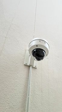 Scène extérieure résidentielle avec caméra de surveillance dôme PTZ au premier plan surveillant une maison moderne à deux étages